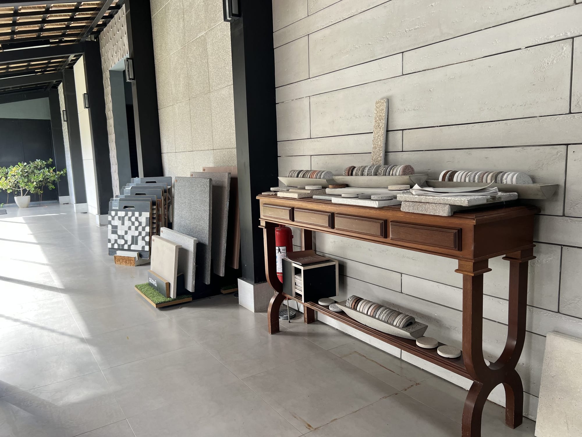Corredor coberto do showroom Piso Decor com aparador e amostras de pedras naturais